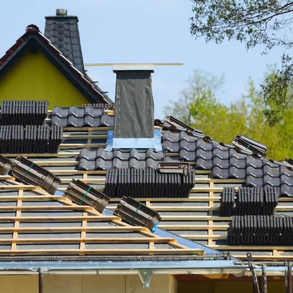New tiled roof installation underway by Roofing Guys Brisbane, showing roof battens, stacked tiles, and chimney flashing in progress. New tiled roof installation underway by Roofing Guys Brisbane, showing roof battens, stacked tiles, and chimney flashing in progress.