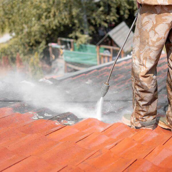 Roofing Guys Brisbane team member pressure cleaning a tiled roof as part of a residential roof restoration. Roofing Guys Brisbane team member pressure cleaning a tiled roof as part of a residential roof restoration.