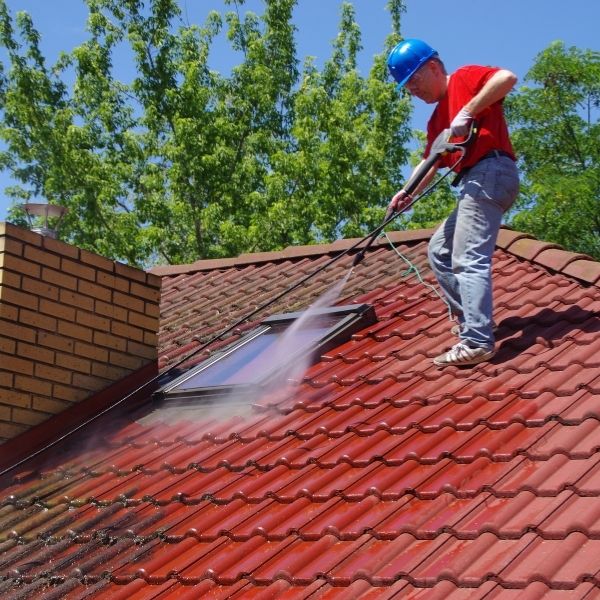 Professional roof cleaning by Roofing Guys Brisbane removing moss and dirt with high-pressure washing.